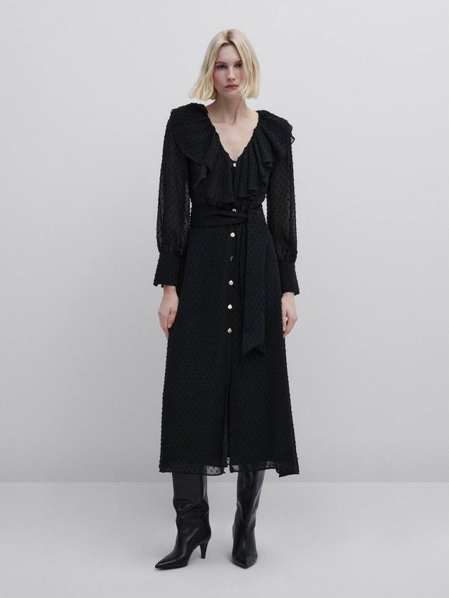 Vestido midi en tejido plumeti vaporoso con manga larga abullonada, falda fluida, cinturón de lazada, escote de pico y volantes, color negro. Hazte con él por 129 euros.