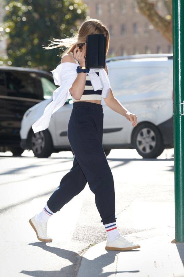 Conjunta un look sport con joggers por 22,95 y camiseta a rayas, con camisa blanca sobre los hombros y bolso baguette.