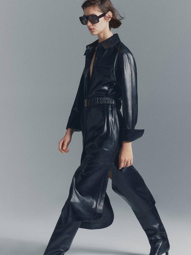 Vestido camisero midi en tejido de piel con manga larga, cuello solapa, aberturas laterales en el bajo, bolsillos, cierre de botones y cinturón ancho elástico, en negro, de Massimo Dutti. Está disponible a 399 euros.