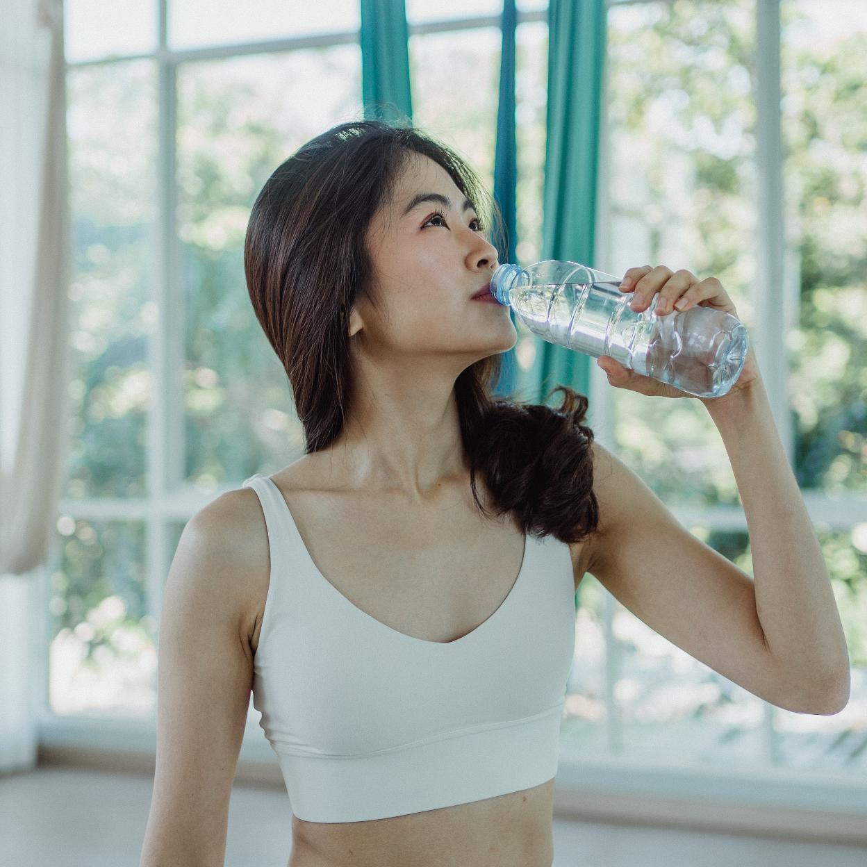 Muejr con ropa deportiva bebiendo agua