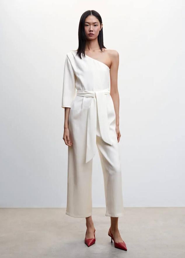 Mono largo con escote asimétrico de una sola manga, cinturón de lazada y perneras anchas, color blanco. Cuesta 49,99 euros.