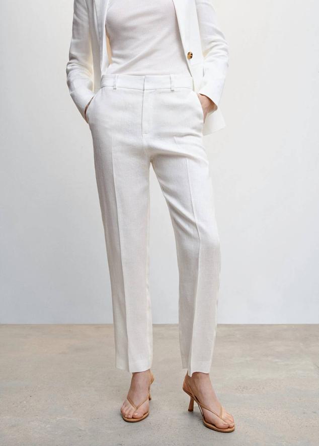 Pantalón de traje en tejido 100% lino con tiro alto, trabilla, bolsillos, raya marcada y perneras rectas, color blanco, de Mango. Lo encontrarás por 39,99 euros.