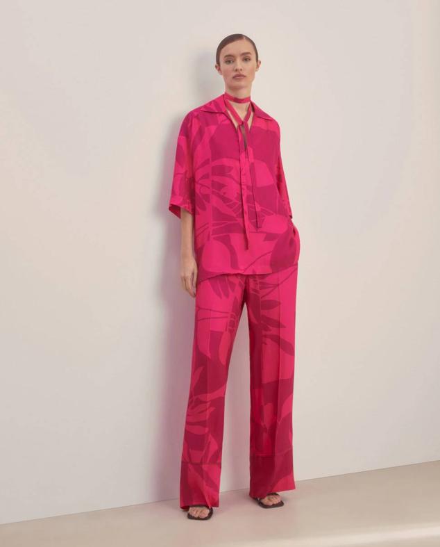 Conjunto con blusa con lazada al cuello y pantalón ancho, en estampado botánico color rosa vivo, de Woman El Corte Inglés. Lo conseguirás por 89,99 euros y 99,99 euros.