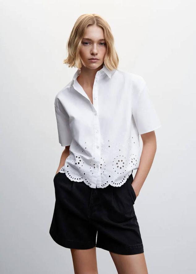 Blusa de algodón con bordado suizo, bajo festoneado, manga corta, cuello solapa y cierre de botones, de Mango. Puedes encontrarla a 25,99 euros.