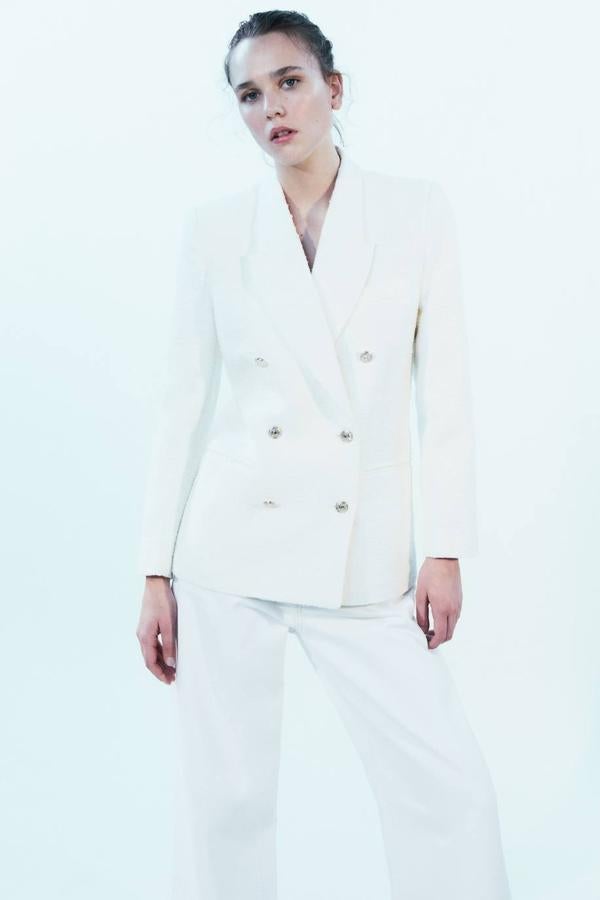 Blazer en tejido de tweed con cuello solapa de pico, manga larga, bolsillos delanteros y cierre de doble botonadura cruzada, en blanco. Podrás comprarla por 49,99 euros.