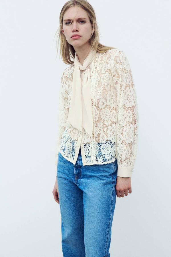 Blusa de encaje con manga larga, cierre de botones y cuello con lazada, en crudo, de Zara. Puedes encontrarla por 22,95 euros.