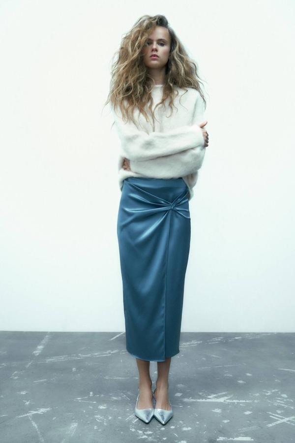 Falda midi en tejido satinado con tiro alto, detalla de nudo central y abertura, tono azul acero, de Zara. La encontrarás a 25,95 euros.