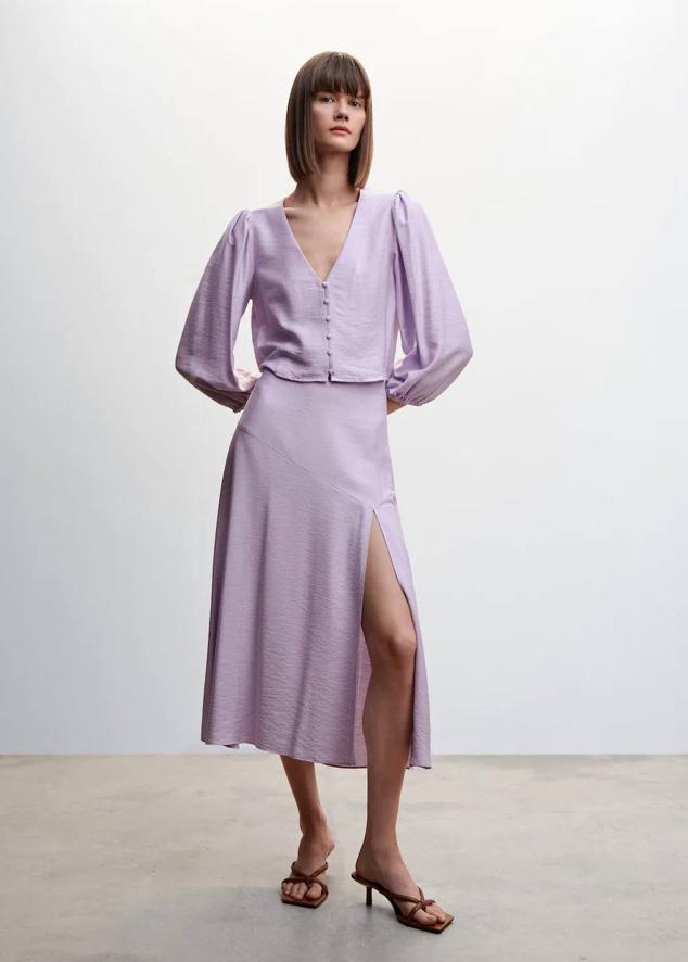 Look en tejido fluido satinado con blusa de manga abullonada y falda midi con abertura, tono lila. Te costará 27,99 euros y 29,99 euros.