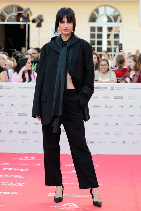 Natalia Lacunza nos sorprende con un look compuesto por un traje negro de corte masculino con un pañuelo satinado anudado al cuello. 