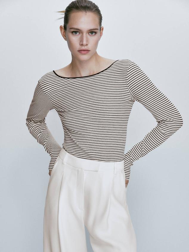 Camiseta de canalé con manga larga, corte ajustado, cuello redondo y escote en la espalda, en print a rayas crudo y negro, de Massimo Dutti. Puedes encontrarla por 29,95 euros.