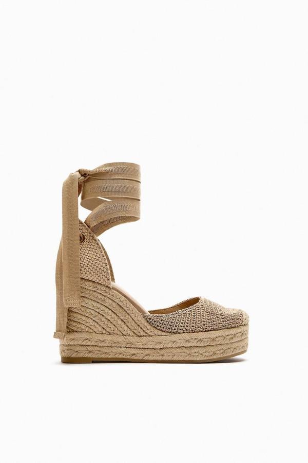 Alpargatas con cuña de esparto, escote redondo, tejido trenzado y cintas para atar al tobillo, tono natural, de Zara. Puedes encontrarlas a 49,95 euros.