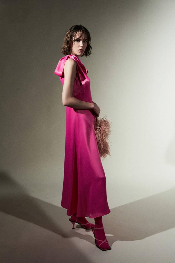 Vestido midi lencero satinado con escote de pico, tirantes con lazada y falda en evasé, color fucsia, de Sfera. Consíguelo por 69,99 euros.