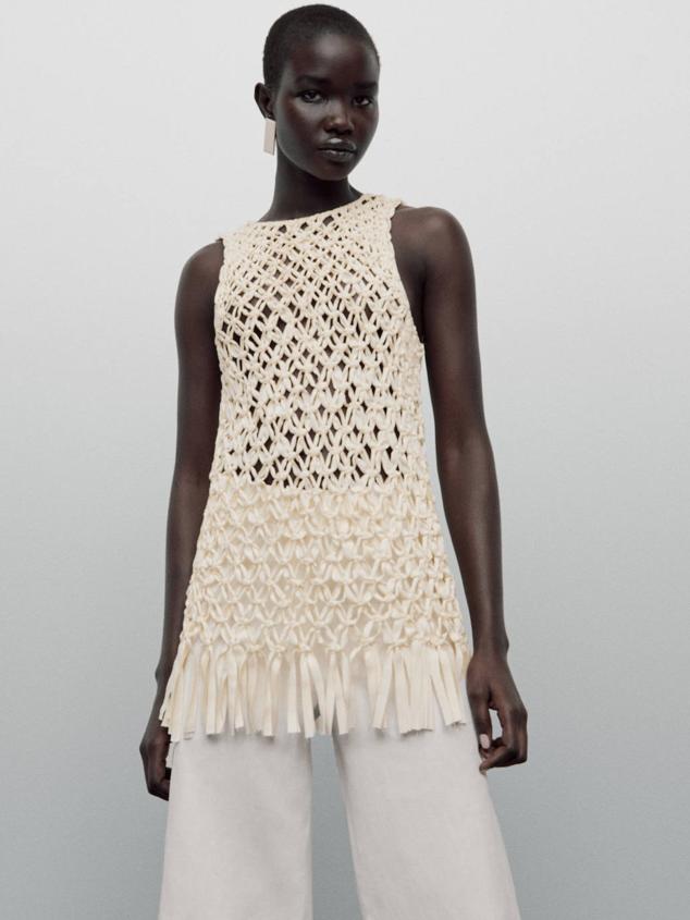Top largo en tejido de punto con manga sisa, cuello redondo y bajo acabado en flecos, tono crudo, de Massimo Dutti. Te costará 99,95 euros.