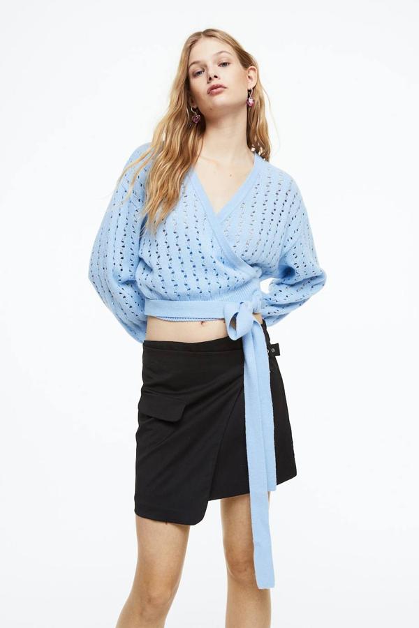 Chaqueta en tejido de punto calado con diseño cruzado, escote de pico, manga larga y cierre de lazada, tono celeste, de H&M. Te costará 24,99 euros.