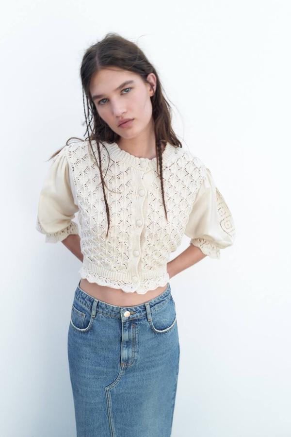 Chaqueta en tejido de punto calado con cuello redondo, cierre de botones, acabados festoneados y mangas abullonadas por debajo del codo, en crudo, de Zara. Cómprala por 29,95 euros.