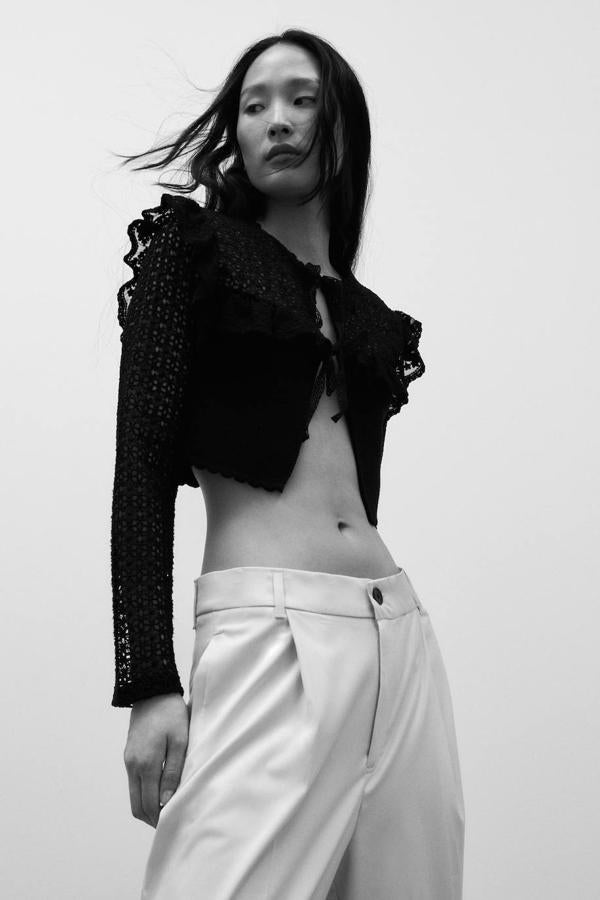 Chaqueta en tejido de punto con detalles calados, mangas largas, volantes, cuello redondo y cierre de lazada, color negro, de Zara. La encontrarás a 29,95 euros.
