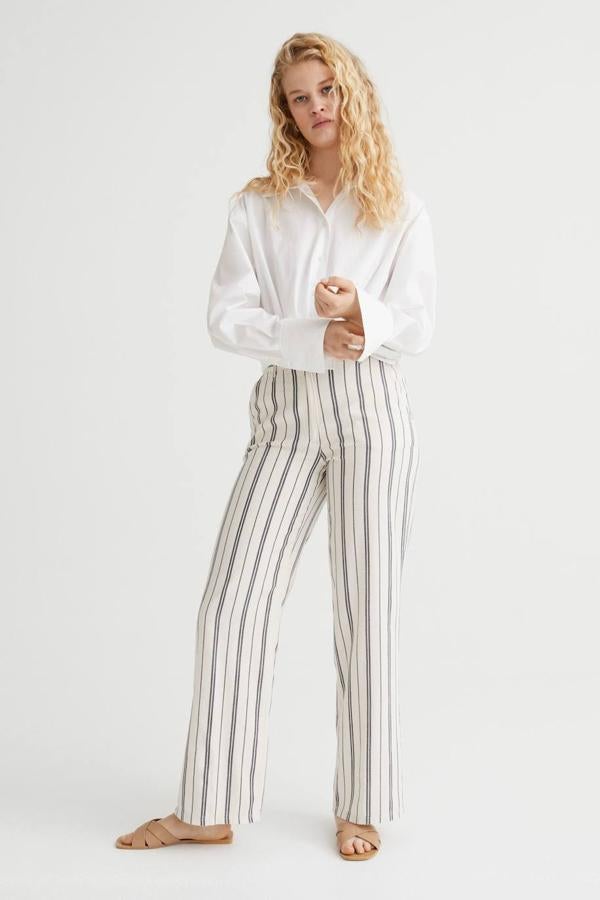 Pantalón recto en tejido mezcla de lino con tiro alto, trabillas, cintura elástica y bolsillos, en print a rayas crudo y azul, de H&M. Puedes comprarlo por 24,99 euros.