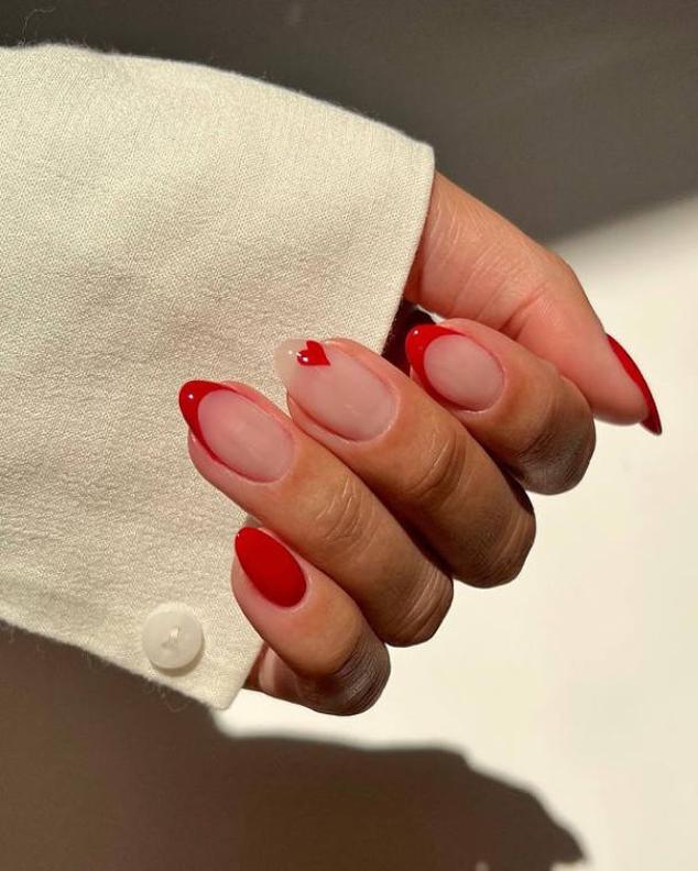 Dibuja un corazón rojo en alguna de tus uñas, sobre una base de esmalte natural y combínalo con otras uñas rojas.