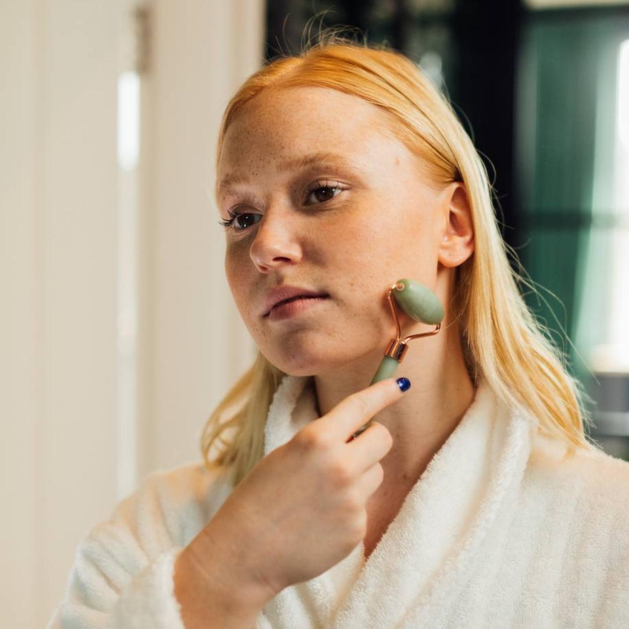 Mujer realizando masaje facial con rodillo de jade