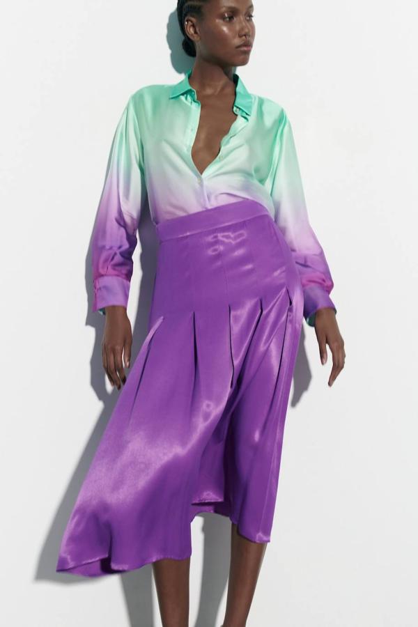 Falda midi en tejido satinado con tiro alto y diseño de tablas, tono morado, de Zara. Puedes encontrarla por 29,95 euros.