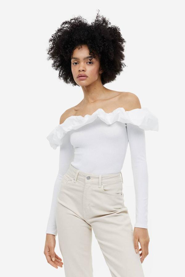 Top en tejido de canalé elástico con manga larga, escote recto, hombros al descubierto y adorno de maxi volante, tono blanco, de H&M. Su precio es de 19,99 euros.