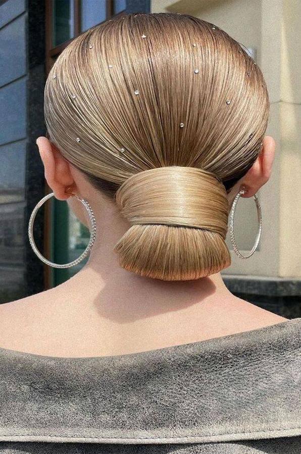 Esta es una de las tendencias de peinados más populares en redes sociales y aportará mucho glamour y modernidad a tu look. Lo puedes realizar en cualquier tipo de moño, pero queda mucho mejor si tiene un acabado tirante y pulido. Para hacerlo, compra  cristales  con pegatina u otro tipo de pedrería suelta y fíjalos al cabello, disponiéndolos como desees, con el mismo adhesivo del cristal, con pegamento para pestañas o con laca.