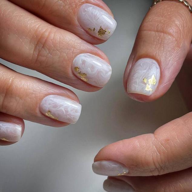 Sin duda, una de las  tendencias de uñas para verano 2023  más populares. Es una especie de diseño  milky nails . Para realizarlo escogeremos un esmalte blanco con efecto nacarado o perlado y lo dispondremos en la uña, haciendo ondulaciones con un pincel. Además, podemos aplicar poro o lámina de oro para decorar. Es una técnica difícil de hacer en casa por lo que es mejor que se la pidas a tu manicurista profesional.