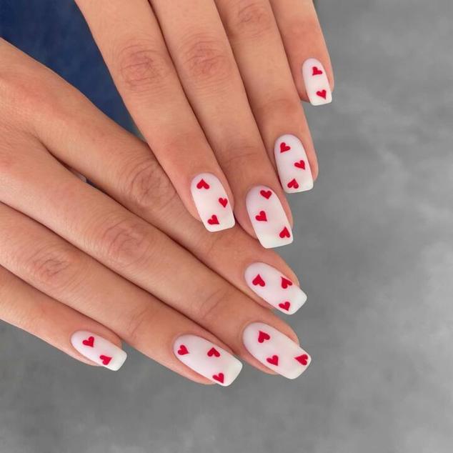 Este modelo de uñas no pasa de moda y es divertido, ponible y perfecto para alegrar tus manos. Pinta las uñas con esmalte blanco. Cuando seque, dibuja varios corazones rojos pequeños con un pincel, en una, varias o todas las uñas. Por último, aplica un esmalte transparente para aumentar el brillo y perfeccionar el acabado.