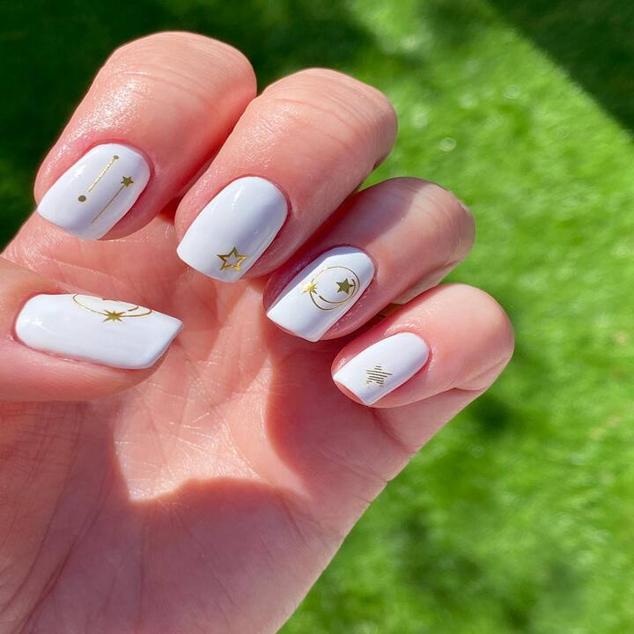 Una de las decoraciones de uñas más fáciles. Lo único que tienes que hacer es pintar las uñas con esmalte blanco para que queden del todo opacas. Después, elegiremos cualquier dibujo de  pegatina de uñas , con acabado metalizado que se llevan mucho o coloridas, lo pegamos con pinzas y añadimos top coat.
