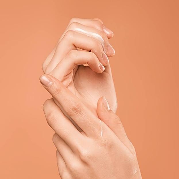 Mujer extendiendo crema hidratante de manos