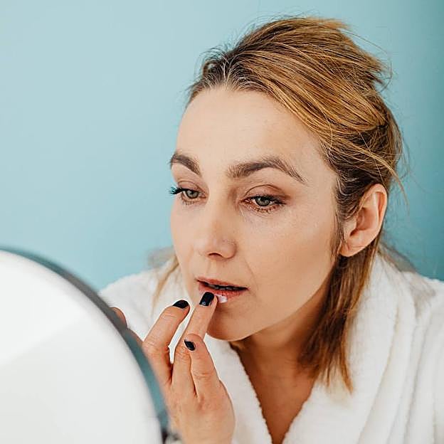 Mujer aplicando vaselina para la cara en la zona de los labios
