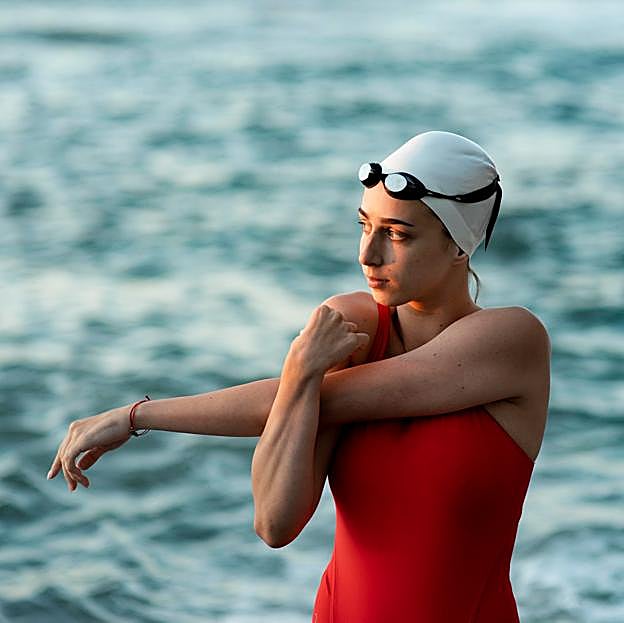 Mujer estirando antes de practicar natación. 