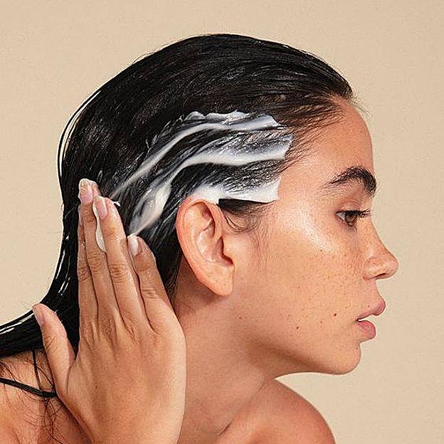Modelo aplicando mascarilla en el pelo