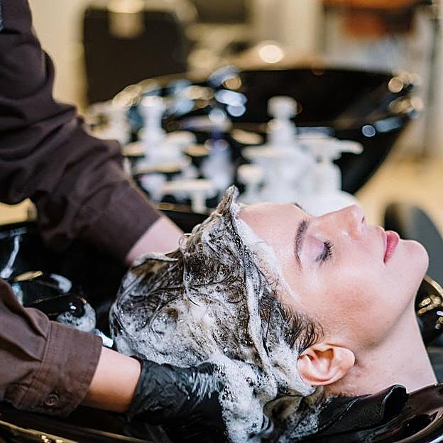 Mujer enjuagándose el pelo tras usar mascarilla antes del champú