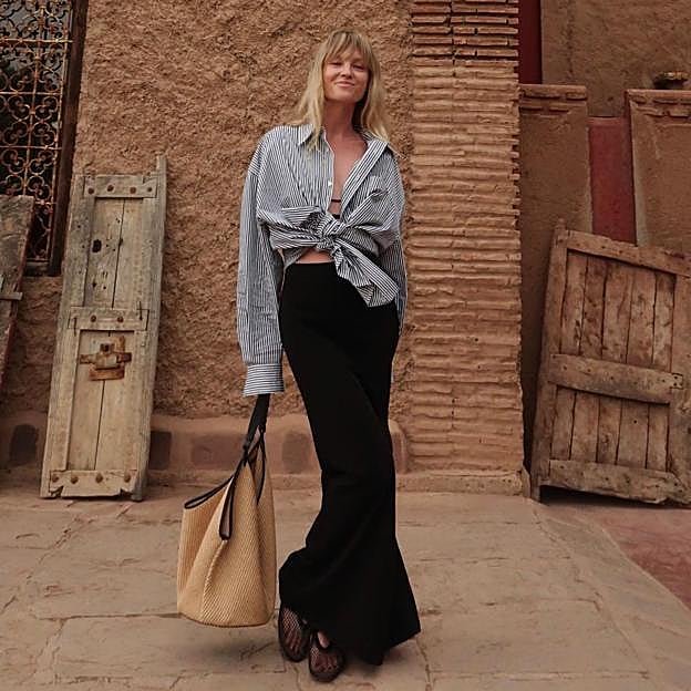 Jeanette Madsein con falda midi, camisa rayas y bailarinas de rejilla.