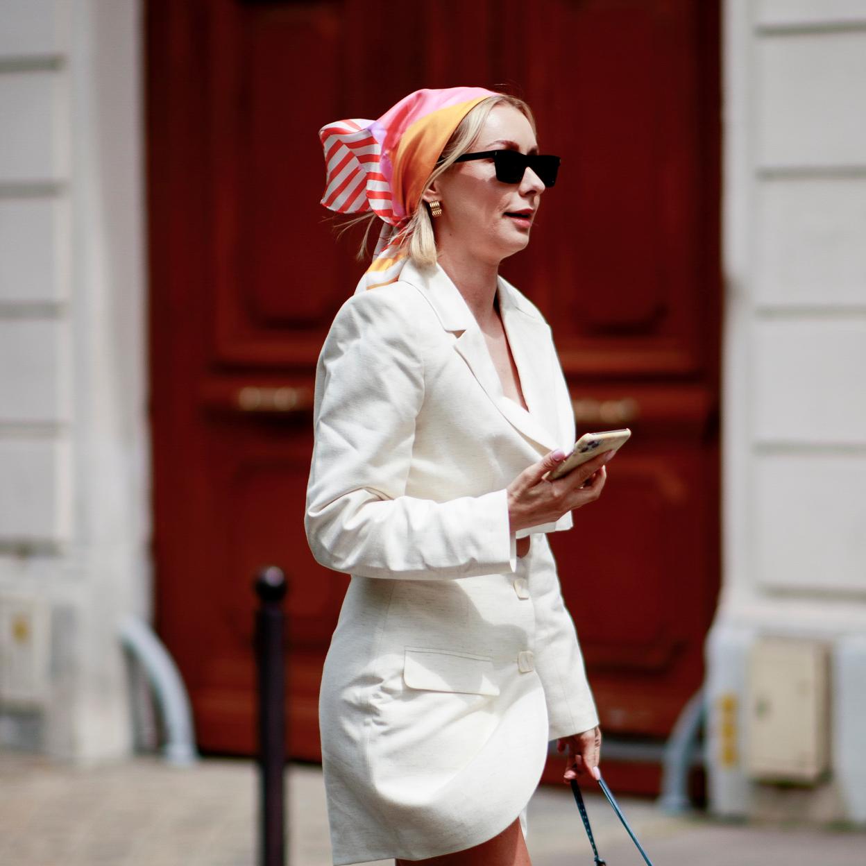 Una mujer caminando con el móvil en la mano.