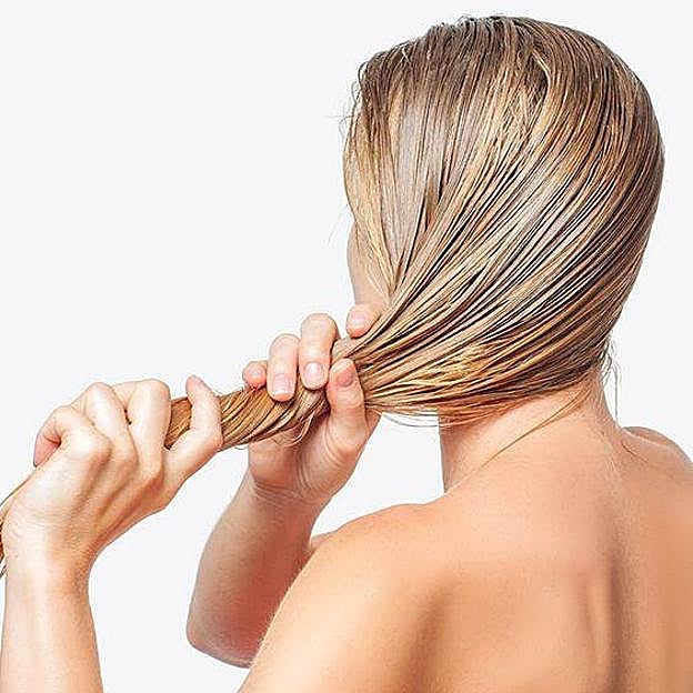 Mujer aplicando mascarilla hidratante para pelo seco