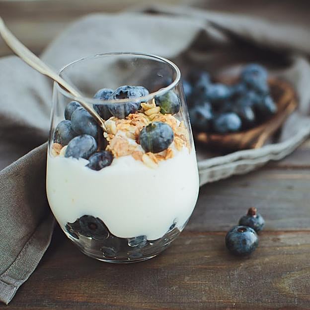 Yogur griego con arándanos frescos y granola. 
