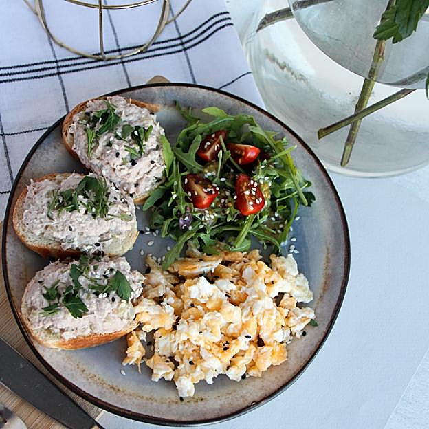 Plato de huevos revueltos con tostadas y vegetales. 