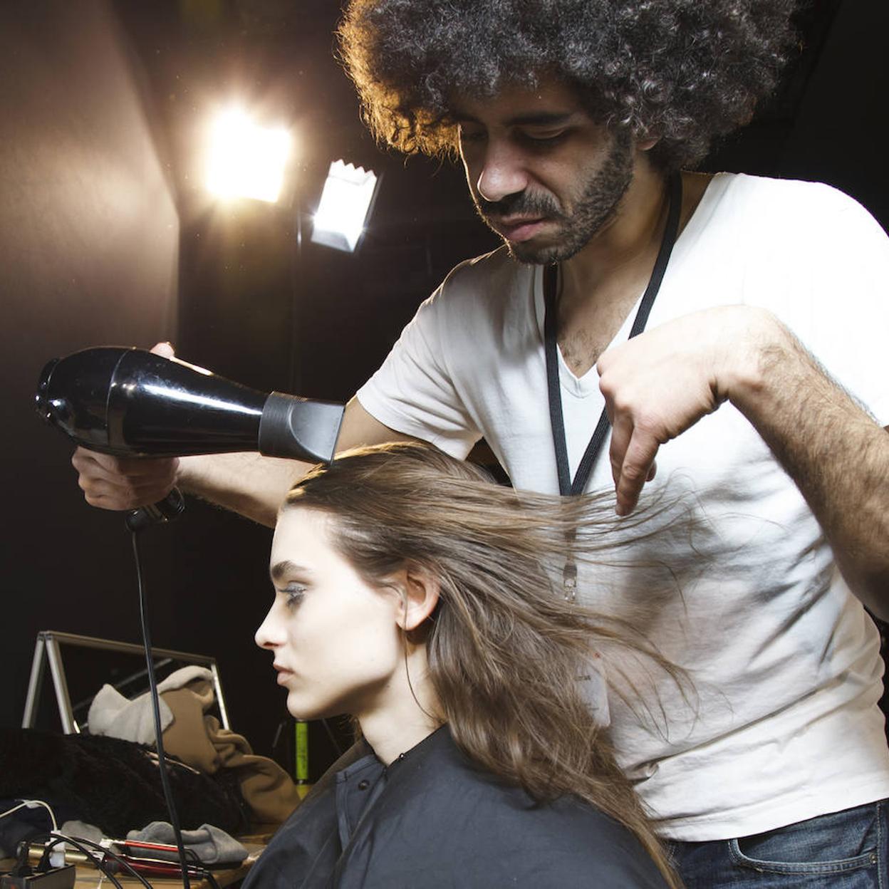 Profesional utilizando secador de pelo en una modelo