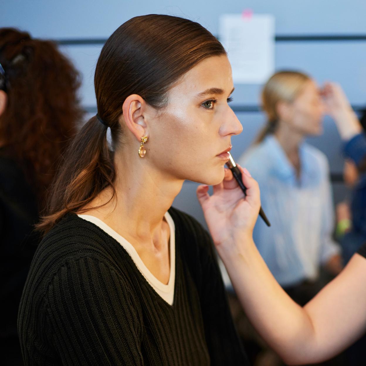 Una modelo maquillándose en el backstage.