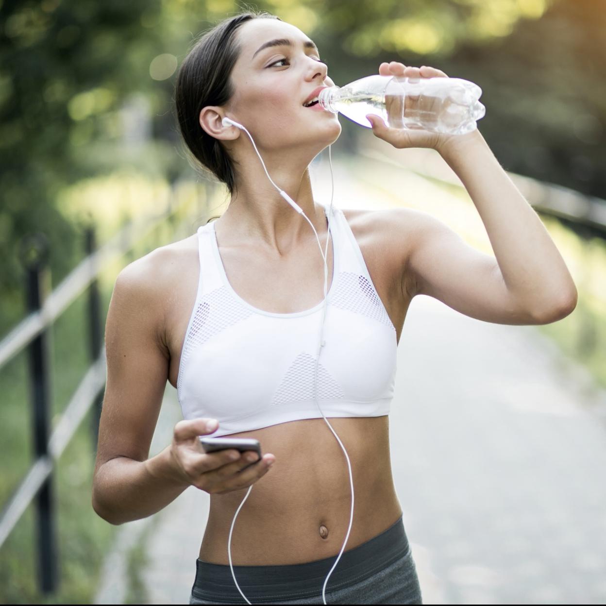 Mujer bebiendo agua después de hacer deporte. 