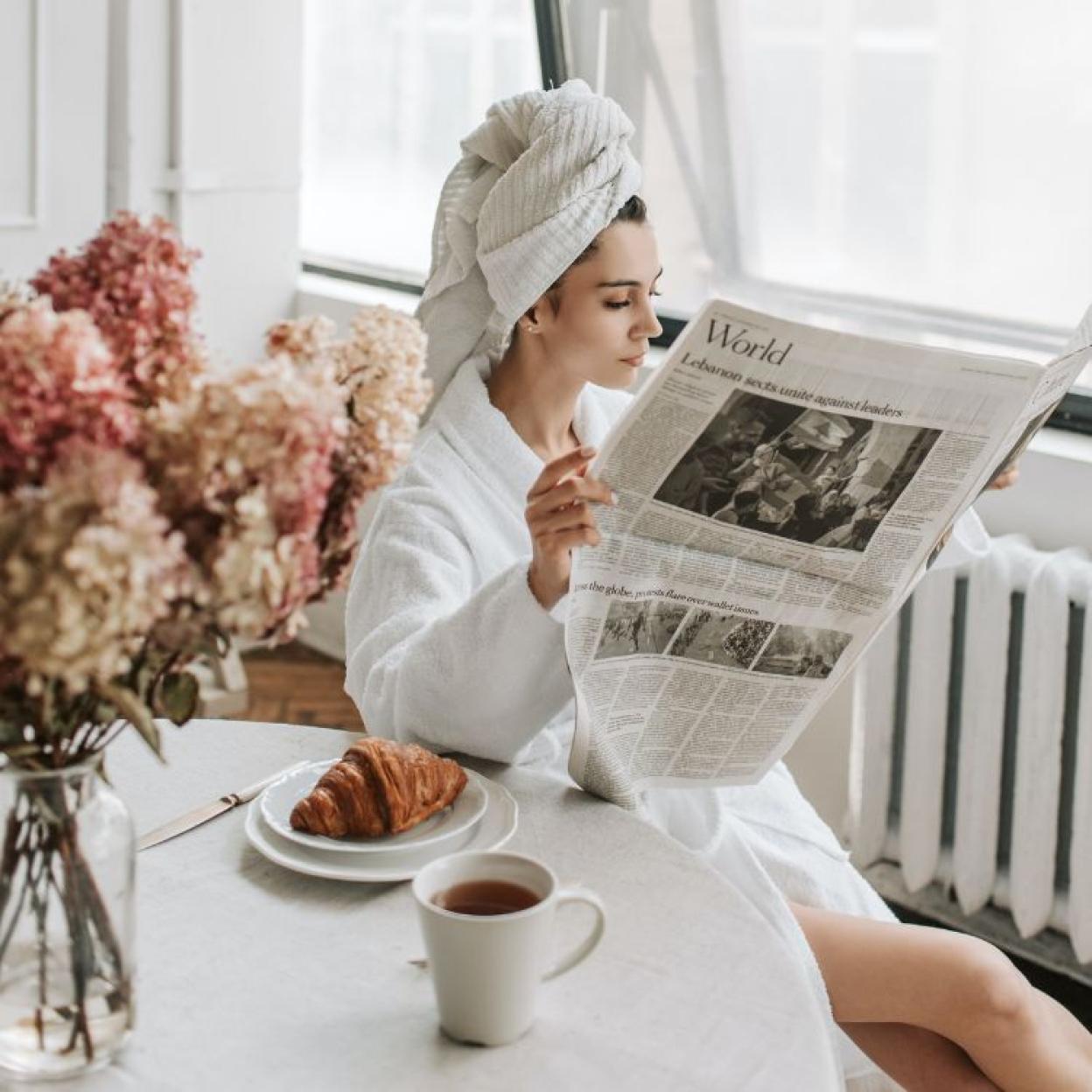 Mujer leyendo la sección de finanzas de un periodico.