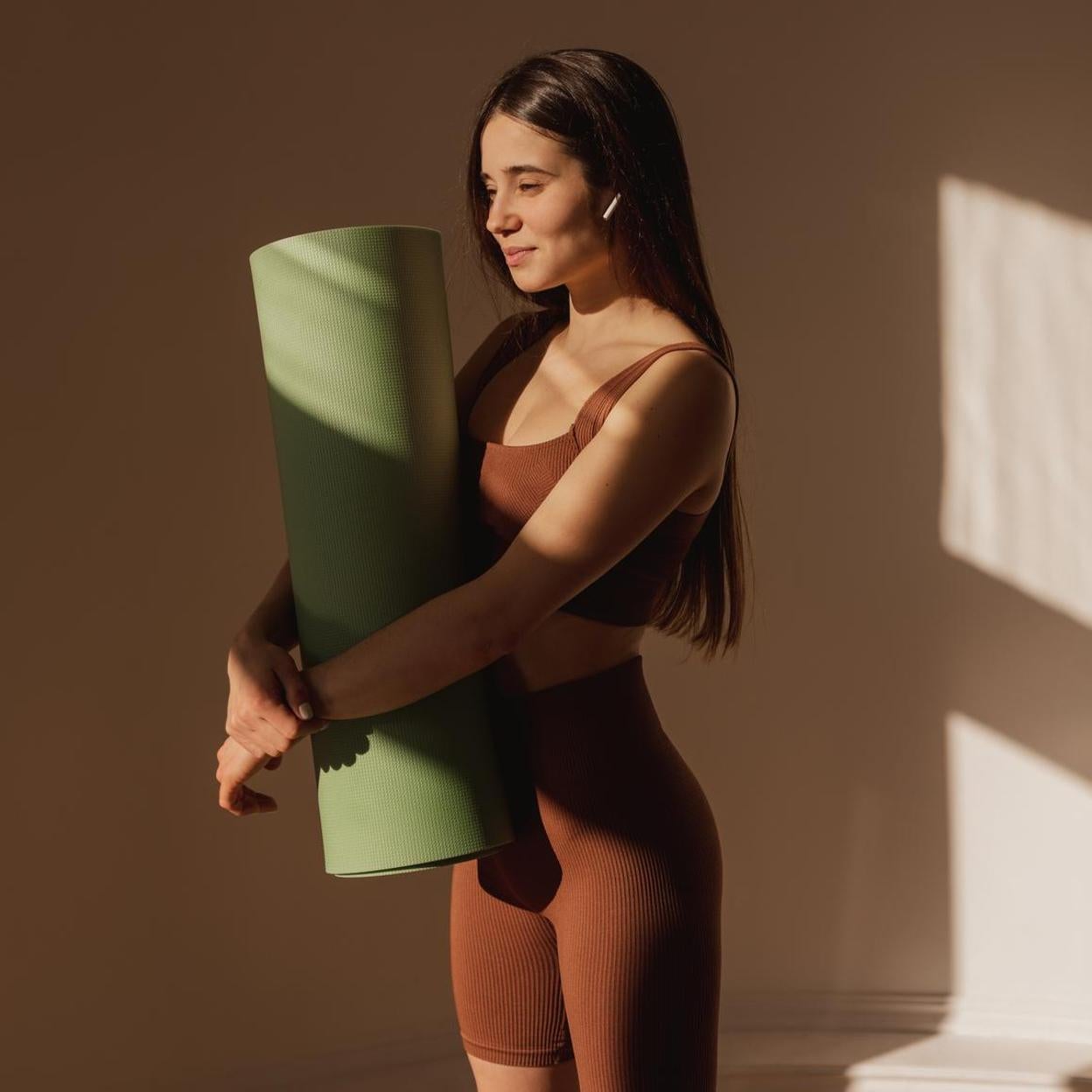 Mujer joven con una esterilla esperando para practicar pilates. 