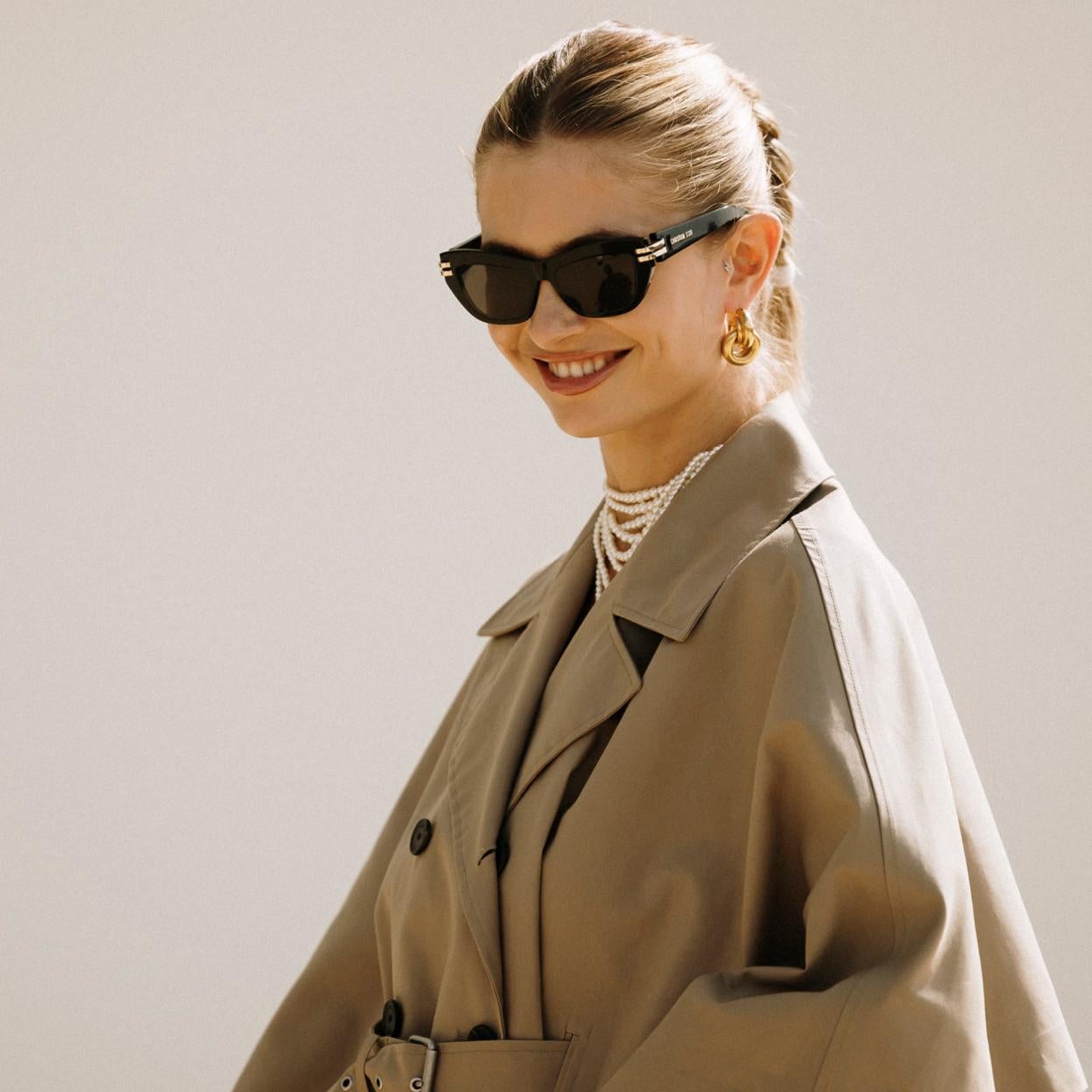 Mujer con gabardina y collar de perlas