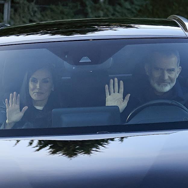 Los reyes saludan a los fotógrafos desde el coche.