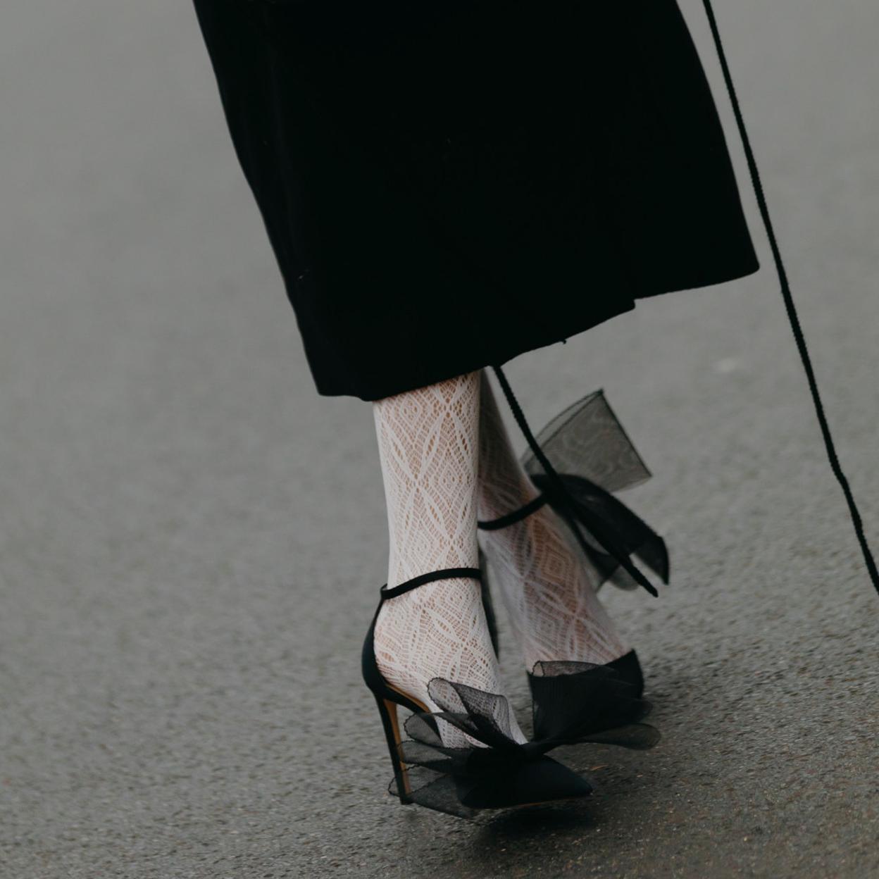 Una mujer con medias blancas y zapatos en negro.