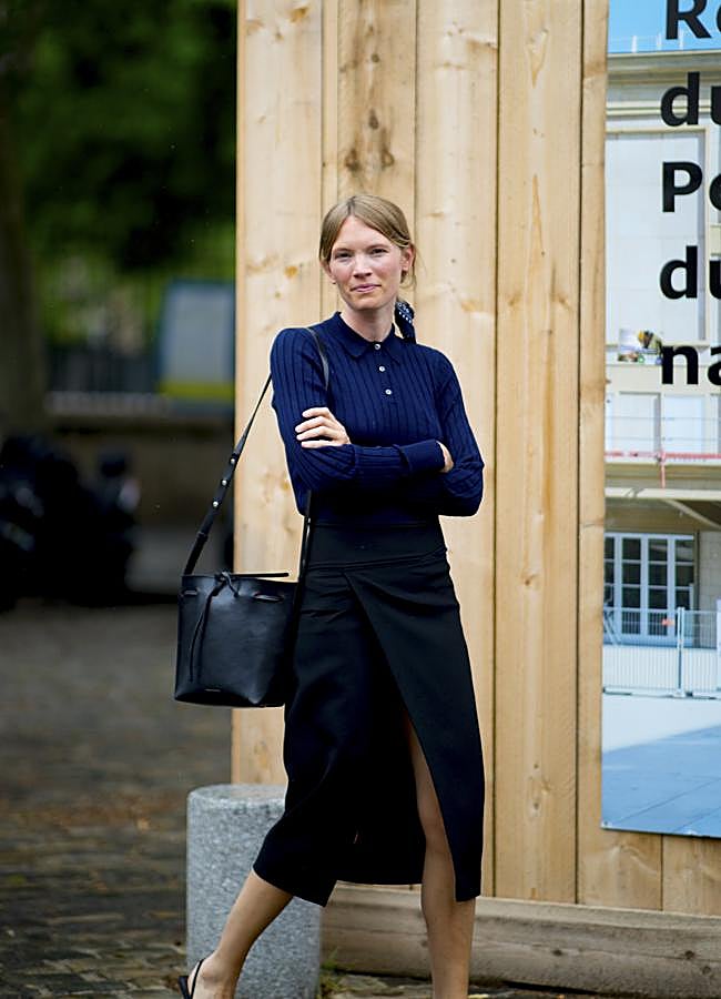 Imagen - Una mujer con polo en azul marino y accesorios en negro.