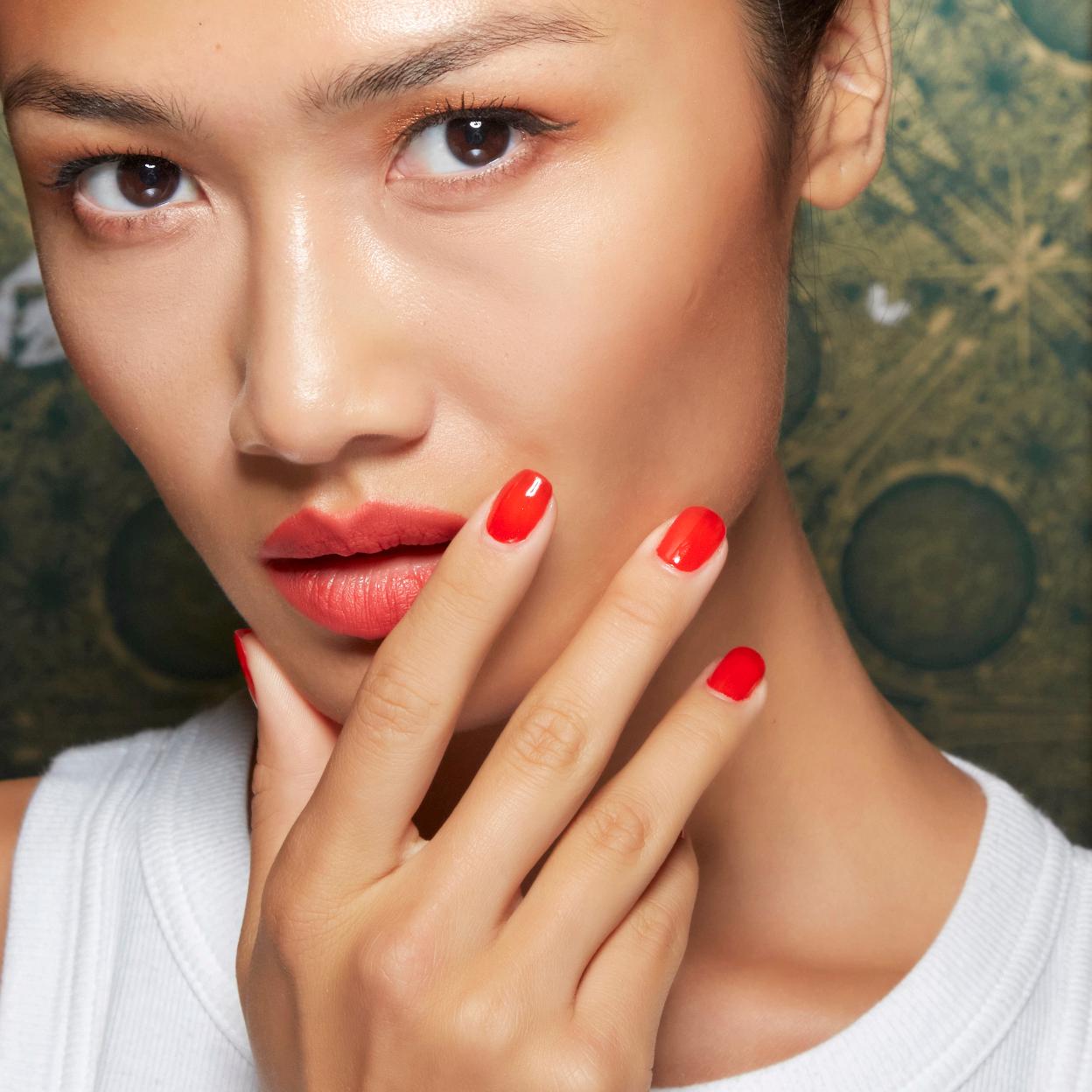 Una modelo con una manicura de color rojo.