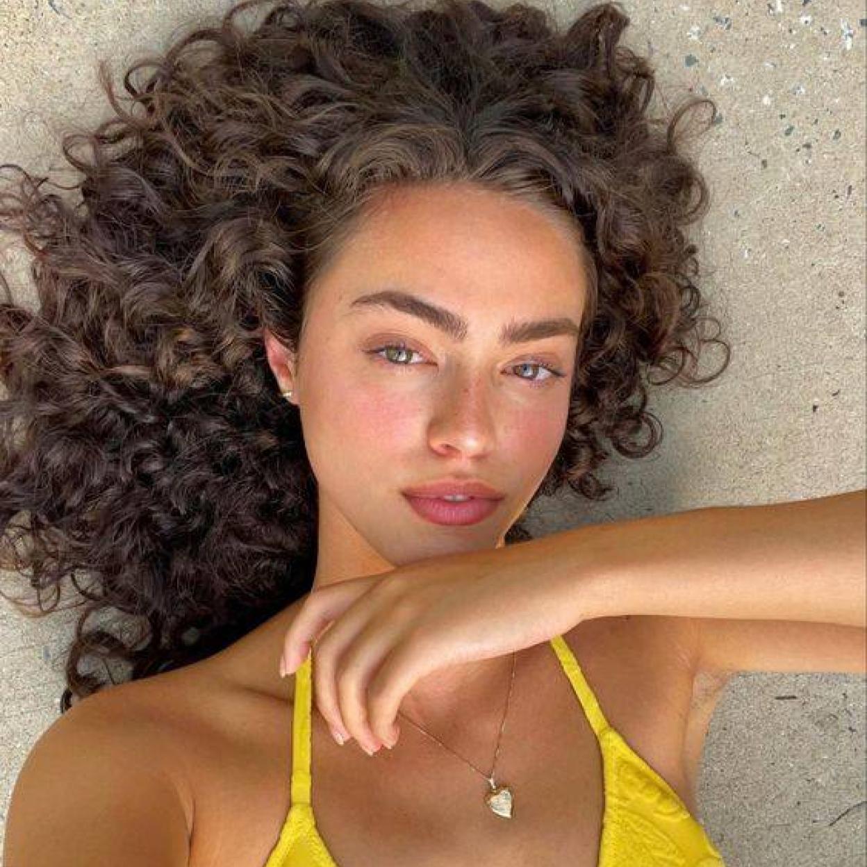 Influencer con pelo rizado en la playa